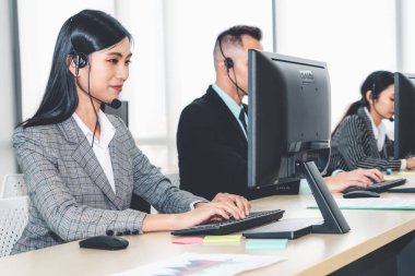 Ofiste çalışan kulaklık takan işadamları uzak müşteri ya da meslektaşlarını desteklemek için çalışıyorlar. Arama merkezi, tele pazarlama, müşteri destek acentesi telefon görüşmesinde hizmet sunar.