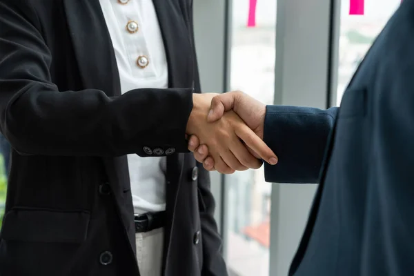 Business people handshake in corporate office showing professional agreement on a financial deal contract.