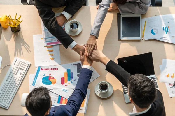 Happy business people celebrate teamwork success together with joy at office table shot from top view . Young businessman and businesswoman workers express cheerful victory showing unity and support .