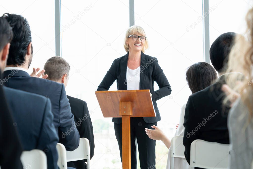 Group of business people meeting in a seminar conference . Audience listening to instructor in employee education training session . Office worker community summit forum with expert speaker .