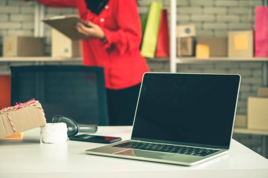 Nakliye kutusunun arka planında boş ekranı olan dizüstü bilgisayar. Çevrimiçi perakende satış mağazası, teslimat siparişi ve müşteri hizmetleri kavramı.