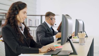 Ofiste çalışan kulaklık takan işadamları uzak müşteri ya da meslektaşlarını desteklemek için çalışıyorlar. Arama merkezi, tele pazarlama, müşteri destek acentesi telefon görüşmesinde hizmet sunar.