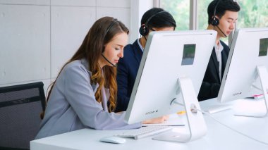 Ofiste çalışan kulaklık takan işadamları uzak müşteri ya da meslektaşlarını desteklemek için çalışıyorlar. Arama merkezi, tele pazarlama, müşteri destek acentesi telefon görüşmesinde hizmet sunar.