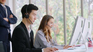 Ofiste çalışan kulaklık takan işadamları uzak müşteri ya da meslektaşlarını desteklemek için çalışıyorlar. Arama merkezi, tele pazarlama, müşteri destek acentesi telefon görüşmesinde hizmet sunar.