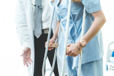 Doktor hastanede koltuk değnekli hastayla ilgileniyor. Fizyoterapist ve bacak yaralanması konsepti.