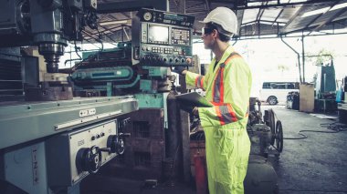 Fabrika atölyesinde makine kullanan akıllı bir fabrika işçisi. Endüstri ve mühendislik kavramı.