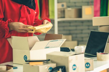 Çevrimiçi satıcı ev ofisinde çalışıyor ve teslimat kutusunu müşteriye paketliyor. İnternette e-ticaret yapan küçük işletme sahibi ya da girişimci.