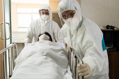 Acil servis doktoru ve doktor hastayı hastanedeki acil servise götürüyor. Doktor koronavirüs ve covid 19 koruma ve karantina kavramında koruyucu giysi ve yüz maskesi takıyor. .
