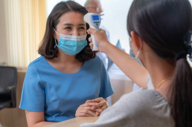 Ofiste ya da hastanede konuşurken resepsiyonist ve misafir maske takıyor. Covid 19 ve Coronavirus enfeksiyon koruması ve koruma politikası kavramı .