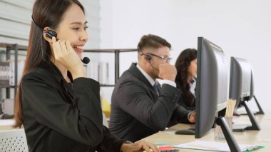 Ofiste çalışan kulaklık takan işadamları uzak müşteri ya da meslektaşlarını desteklemek için çalışıyorlar. Arama merkezi, tele pazarlama, müşteri destek acentesi telefon görüşmesinde hizmet sunar.