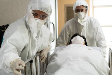 Acil servis doktoru ve doktor hastayı hastanedeki acil servise götürüyor. Doktor koronavirüs ve covid 19 koruma ve karantina kavramında koruyucu giysi ve yüz maskesi takıyor. .