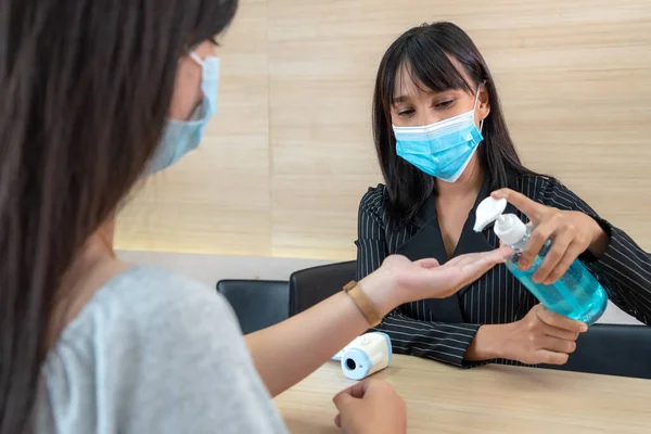 Receptionist and guest wearing face mask at front desk while having conversation in office or hospital . Covid 19 and coronavirus infection protection and protective policy concept .