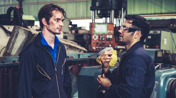 Tired factory workers taking a break and talking to coworker in the factory . Industry and engineering concept .