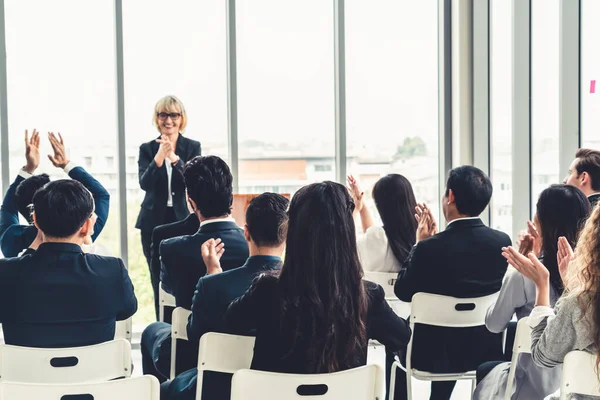 Group of business people meeting in a seminar conference . Audience listening to instructor in employee education training session . Office worker community summit forum with expert speaker .