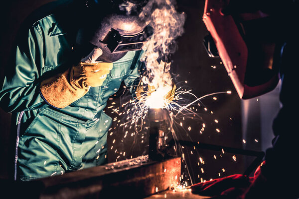 Metal welding steel works using electric arc welding machine to weld steel at factory. Metalwork manufacturing and construction maintenance service by manual skill labor concept.