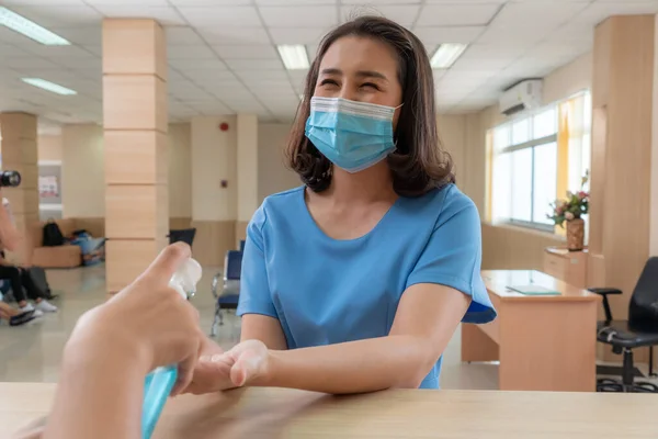 Receptionist and guest wearing face mask at front desk while having conversation in office or hospital . Covid 19 and coronavirus infection protection and protective policy concept .