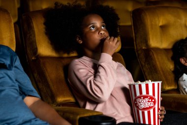 Üç çocuk eğleniyor ve sinemada film izlemekten zevk alıyor.