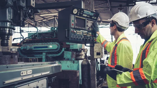 Group of factory workers using machine equipment in factory workshop . Industry and engineering concept .