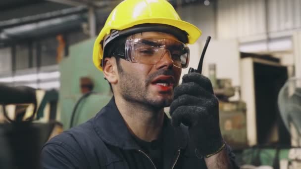 Pracownik fabryki rozmawia przez przenośne radio podczas kontroli części maszyn — Wideo stockowe