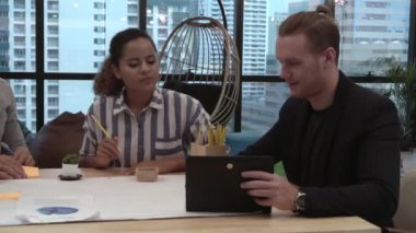 Yaratıcı iş adamları grubu iş yerindeki ofis masasında sohbet ediyorlar..