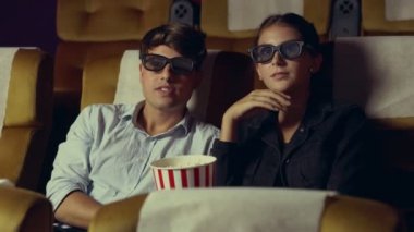 Sinemada erkek ve kadın 3 boyutlu film izliyor.
