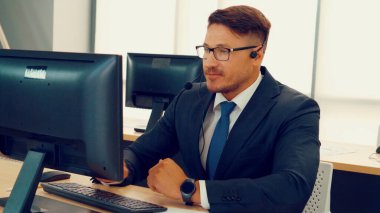 Ofiste çalışan kulaklık takan işadamları uzak müşteri ya da meslektaşlarını desteklemek için çalışıyorlar. Arama merkezi, tele pazarlama, müşteri destek acentesi telefon görüşmesinde hizmet sunar.