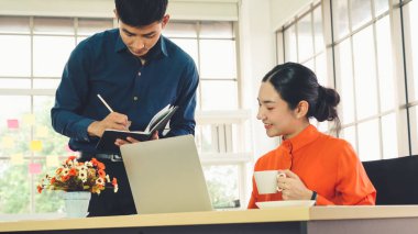 İki iş adamı toplantı odasında proje stratejisi hakkında konuşuyor. İş adamı, mali veri raporu hakkında sohbet ve tavsiyelerde bulunurken, modern işyerindeki iş arkadaşıyla proje planlamasını tartıştı.