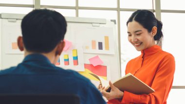 Genç bir kadın günlük ofis odasındaki beyaz tahtadaki iş verilerini açıklıyor. Kendine güvenen Asyalı işkadını, pazar stratejisini belirlemek için ortak olarak yürütülen bir iş projesinin bilgi ilerlemesini rapor etti .