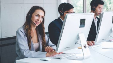 Ofiste çalışan kulaklık takan işadamları uzak müşteri ya da meslektaşlarını desteklemek için çalışıyorlar. Arama merkezi, tele pazarlama, müşteri destek acentesi telefon görüşmesinde hizmet sunar.