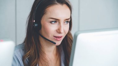 Ofiste çalışan kulaklık takan işadamları uzak müşteri ya da meslektaşlarını desteklemek için çalışıyorlar. Arama merkezi, tele pazarlama, müşteri destek acentesi telefon görüşmesinde hizmet sunar.