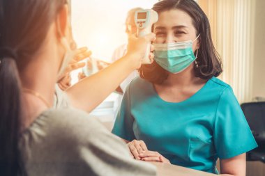 Ofiste ya da hastanede konuşurken resepsiyonist ve misafir maske takıyor. Covid 19 ve Coronavirus enfeksiyon koruması ve koruma politikası kavramı .