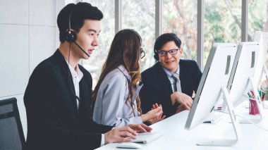 Ofiste çalışan kulaklık takan işadamları uzak müşteri ya da meslektaşlarını desteklemek için çalışıyorlar. Arama merkezi, tele pazarlama, müşteri destek acentesi telefon görüşmesinde hizmet sunar.