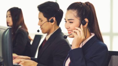 Ofiste çalışan kulaklık takan işadamları uzak müşteri ya da meslektaşlarını desteklemek için çalışıyorlar. Arama merkezi, tele pazarlama, müşteri destek acentesi telefon görüşmesinde hizmet sunar.