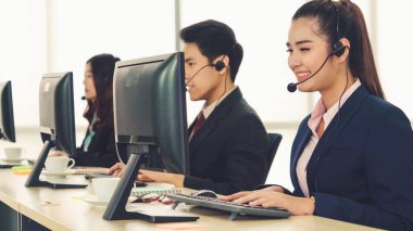 Ofiste çalışan kulaklık takan işadamları uzak müşteri ya da meslektaşlarını desteklemek için çalışıyorlar. Arama merkezi, tele pazarlama, müşteri destek acentesi telefon görüşmesinde hizmet sunar.