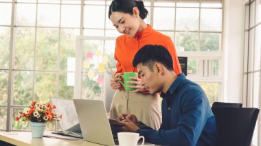 İki iş adamı toplantı odasında proje stratejisi hakkında konuşuyor. İş adamı, mali veri raporu hakkında sohbet ve tavsiyelerde bulunurken, modern işyerindeki iş arkadaşıyla proje planlamasını tartıştı.