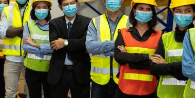 Bir grup fabrika işçisi Covid-19 Coronavirus 'un iş açılışında yayılmasını önlemek için maske takıyor. .