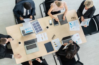 İş adamları grup toplantısı ofiste yukarıdan çekildi. İş kadınları, iş adamları ve ofis çalışanları, proje planlama belgeleriyle takım konferansında toplantı masasında çalışıyorlar. .