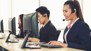 Ofiste çalışan kulaklık takan işadamları uzak müşteri ya da meslektaşlarını desteklemek için çalışıyorlar. Arama merkezi, tele pazarlama, müşteri destek acentesi telefon görüşmesinde hizmet sunar.