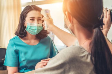 Ofiste ya da hastanede konuşurken resepsiyonist ve misafir maske takıyor. Covid 19 ve Coronavirus enfeksiyon koruması ve koruma politikası kavramı .