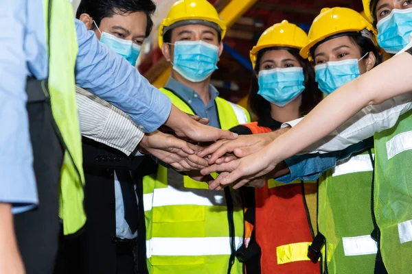 Group of factory industry worker working with face mask to prevent Covid-19 Coronavirus spreading during job reopening period .