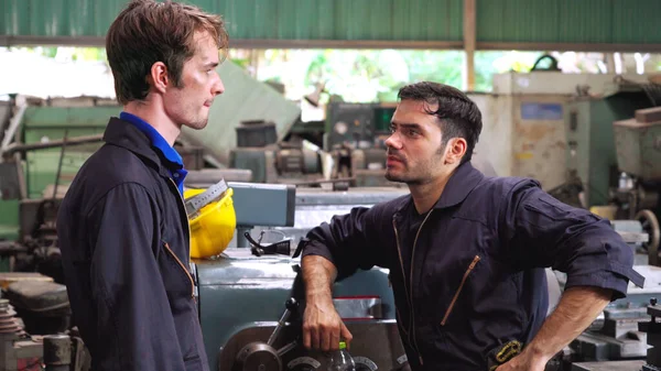 Yorgun fabrika işçileri mola verip fabrikada iş arkadaşlarıyla konuşuyorlar. Endüstri ve mühendislik kavramı .