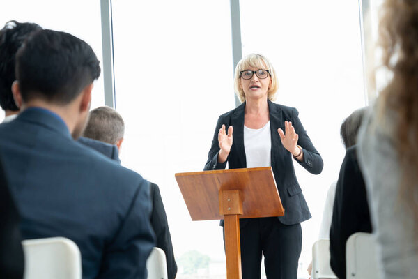 Group of business people meeting in a seminar conference . Audience listening to instructor in employee education training session . Office worker community summit forum with expert speaker .