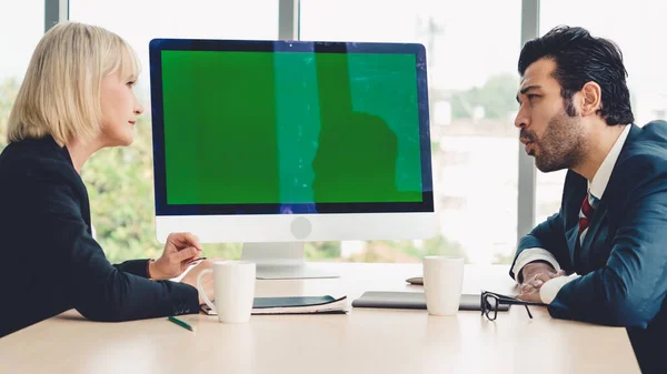 Business people in the conference room with green screen chroma key TV or computer on the office table. Diverse group of businessman and businesswoman in meeting on video conference call .