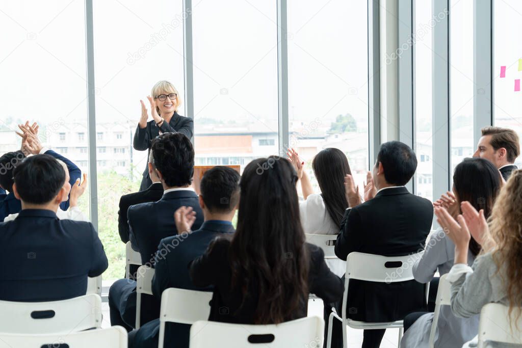 Group of business people meeting in a seminar conference . Audience listening to instructor in employee education training session . Office worker community summit forum with expert speaker .