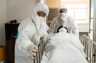 Acil servis doktoru ve doktor hastayı hastanedeki acil servise götürüyor. Doktor koronavirüs ve covid 19 koruma ve karantina kavramında koruyucu giysi ve yüz maskesi takıyor. .