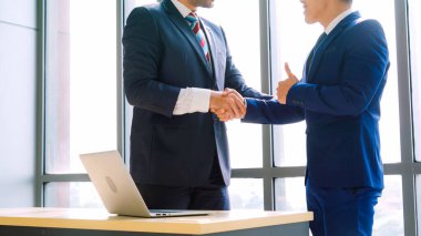 Şirket ofisinde iş adamlarının el sıkışması mali anlaşma konusunda profesyonel bir anlaşma gösteriyor.