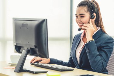 Ofiste çalışan kulaklık takan işadamları uzak müşteri ya da meslektaşlarını desteklemek için çalışıyorlar. Arama merkezi, tele pazarlama, müşteri destek acentesi telefon görüşmesinde hizmet sunar.