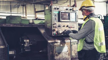 Fabrika atölyesinde makine kullanan akıllı bir fabrika işçisi. Endüstri ve mühendislik kavramı.