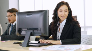 Ofiste çalışan kulaklık takan işadamları uzak müşteri ya da meslektaşlarını desteklemek için çalışıyorlar. Arama merkezi, tele pazarlama, müşteri destek acentesi telefon görüşmesinde hizmet sunar.