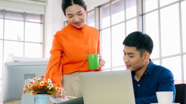 İki iş adamı toplantı odasında proje stratejisi hakkında konuşuyor. İş adamı, mali veri raporu hakkında sohbet ve tavsiyelerde bulunurken, modern işyerindeki iş arkadaşıyla proje planlamasını tartıştı.